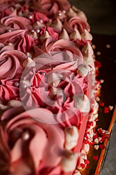 Pink heart-shaped cake decorated with cream in the form of curls and roses