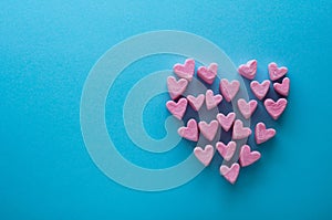 Pink heart-shaped marshmallows stacked on a blue background with space for copy. Marshmallow heart.Valentine`s day concept theme