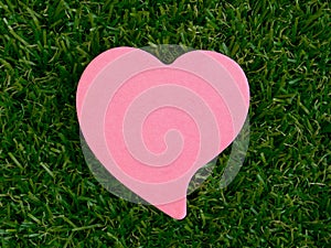 Pink heart-shaped notpad on the artificial grass