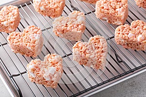 Pink heart shaped rice krispie treats on a cooling rack
