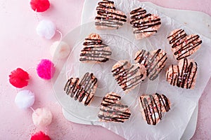 Pink heart shaped rice krispie treats drizzled with dark chocolate on a marble board