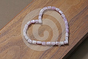 Pink heart on a wooden background. Kunzite is a natural pink sto