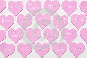 Pink hearts with text LOVE, KISS, FOREVER YOURS on white background. Valentines day texture or wallpaper. Gift for lover