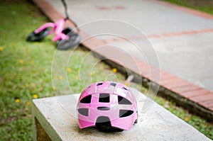 Pink helmet on the concrete bench in the park with pink push bike in the background