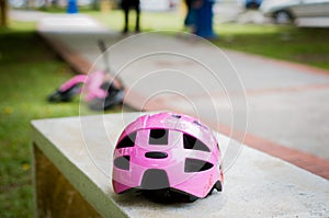 Pink helmet on the concrete bench in the park with pink push bike in the background