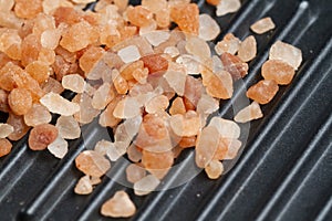 Pink Himalayan grains of salt, on black surface