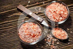 Pink Himalayan rock coarse salt in glass bowls on brown wooden table