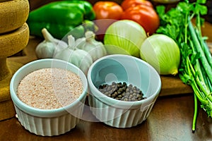 Pink himalayan salt and black pepper in ramekins with garlic, onions, green peppers, tomatoes and parsley and chives