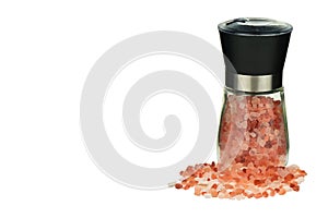 Pink Himalayan salt crystals in a glass grinder. Himalayan pink salt in mill isolated on white background.