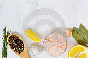 Pink Himalayan salt on the glass bowl, greens, piece of yellow lemon and fresh garlic