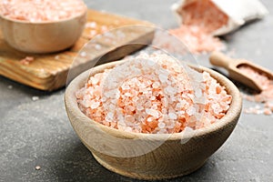 Pink himalayan salt in wooden bowl on grey table