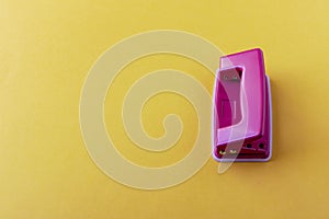 Pink hole punch on a yellow background. Close up