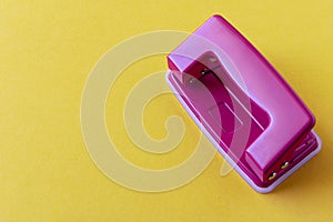 Pink hole punch on a yellow background. Close up