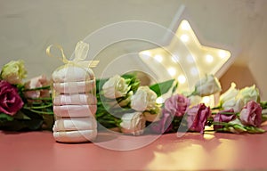 Pink homemade marshmallows tied with a ribbon near fresh flowers, tenderness concept. Valentine`s Day. Selective focus.
