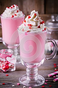 Pink hot chocolate with whipped cream and sugar hearts in a glass mug for Valentine Day