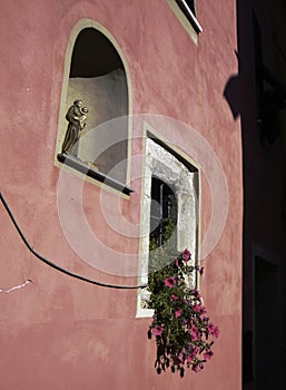 Pink house wall with a niche in which there is a figure of a saint