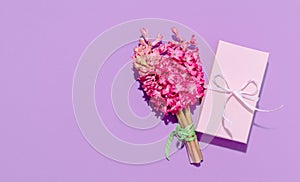 Pink hyacinth spring flowers with gift box on lilac background top view