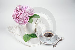 Pink hydrangea in a vase with a cup of coffee