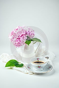 Pink hydrangea in a vase with a cup of coffee