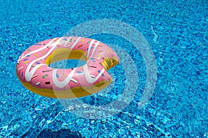 Pink inflatable donut doughnut floating mattress in swimming pool. Beach pool accessories. Summer holiday concept