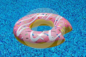 Pink inflatable donut doughnut floating mattress in swimming pool. Beach pool accessories. Summer holiday concept