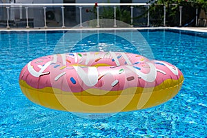 Pink inflatable donut doughnut floating mattress in swimming pool. Beach pool accessories. Summer holiday concept