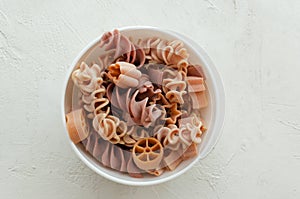 Pink Italian pasta in white bowl on a light background. Concept alternative pasta. Horisontal orientation. copy space.