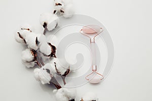 Pink jade roller for face massage on a white table. Anti age, lifting and toning treatment