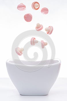 Pink jelly gum drops falling into a white bowl