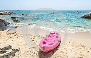 Pink kayaks moored on the beach with turquoise sea in sunny day