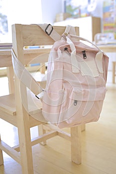 Pink kid backpack hanging on a chair