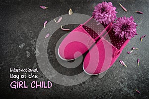 Pink kid shoes and flowers on a dark slate background, text Day