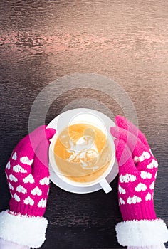 Pink knitted gloves hands hold coffee cup