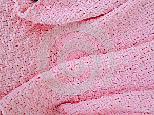 Pink knitted plaid close-up. Background. Creases on soft surfaces