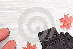 Pink leather boots and black Womens jeans on white wooden background with copy space. Female clothes