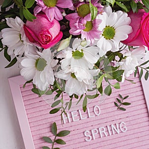 Pink letterboard with quote Hellow Spring and blooming tender bouquet of flowers. Top view. Festive greeting card