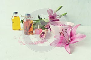 Pink lilies, burning candles, sea salt, oil and tincture of medicinal plants on the table, spa