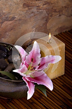 Pink lily flower and candle on bamboo