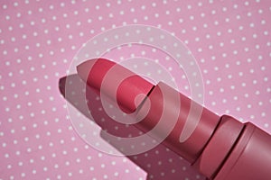 Pink lipstick on a purple polka dot background.