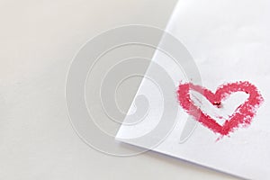 Pink lipstick smeared in heart shape on white paper