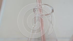 Pink liquid being poured into a test tube through a chemical pipette in a laboratory close up