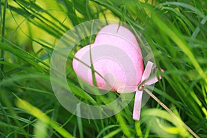 A pink love shaped foam toy gift lying on green grass lawn in summer spring autumn, close up