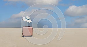 Pink of the luggage with white hat on the beach