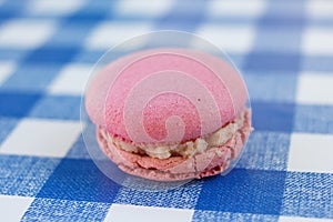 Pink macaron sitting on a blue check pattern