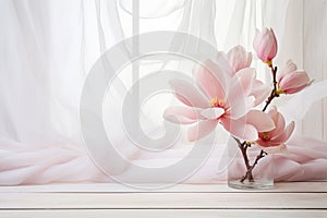 Pink magnolia flowers in glass vase near the window with tulle fabric