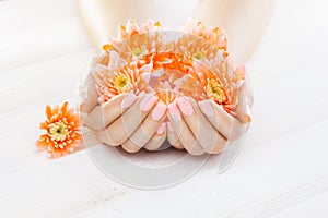 Pink manicure with orange chrysanthemum flowers. spa