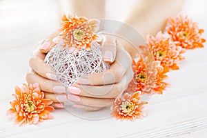 Pink manicure with orange chrysanthemum flowers. spa