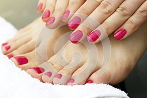 Pink manicure and pedicure on female hands and legs, close-up, side view