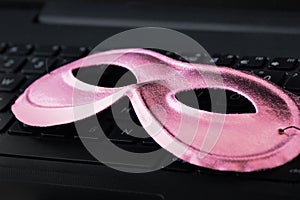 Pink mask on laptop keyboard - Concept of privacy, security and anonymity of women computer users
