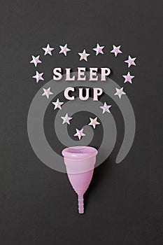 Pink menstrual cup on black background with with heart and words Sleep cup. Concept possibility of use cup at night, zero waste,